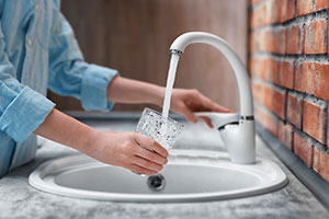 Woman pouring a drink from a tap and not wasting water