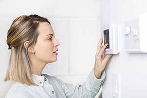 Woman saving hundreds of pounds by turning down the thermostat from Energy Supplier