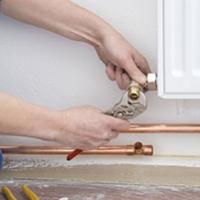 A plumber that has taken on self-employment fixing a radiator A plumber that has taken on self-employment fixing a radiator