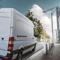 White van driving through a city