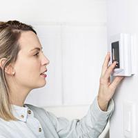 Woman saving hundreds of pounds by turning down the thermostat from Energy Supplier Woman saving hundreds of pounds by turning down the thermostat from Energy Supplier